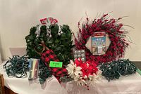 Overview of the lot showing wreaths, lights, ornaments, and power adaptor on a table.
