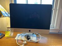 Front view of Apple computer monitor on a desk with keyboard and mouse in front, showing overall condition and setup.