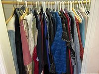 Full view of sweaters and pants on hangers showing a mix of colors including blue, black, red, and gray.