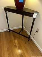 Full view of the dark wooden corner table with turned legs placed against walls, showing overall condition and measurements.