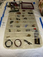 Full view of jewelry items in clear organizer pouches and hooks on bed
