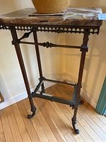 Full view of iron plant stand showing marble top, frame and feet