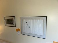 Two framed art prints hanging on a beige wall, showing their display size and framing.