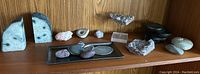 Wide angle showing various rocks and minerals including agate bookends and amethyst clusters on a wooden shelf