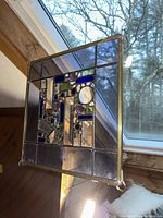 Stained glass panel hanging near a window showing design details and transparent elements.