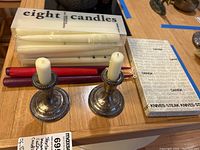 Pair of sterling silver weighted candle holders with assorted white and red taper candles and boxed Dansk carving set on wooden table