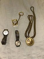 Four watches and one gold-tone pendant necklace on chain arranged showing watch faces and chains.