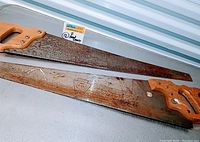 Two vintage handsaws with wooden handles laid side by side showing full blade and handle. One blade marked DISSTON D-23.