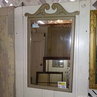 Full view of the tall rectangular cream painted wooden wall mirror with hand-painted floral scroll decoration at the top.