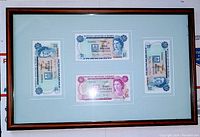 Full view of framed Bermuda banknotes, showing three bills arranged on matte inside wooden frame.