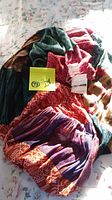 Photo showing full scarf with tags and colorful pattern in red, purple, and green hues spread on fabric surface