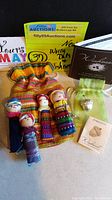 Photo of four colorful hand-sewn worry dolls and a Demdaco strength charm in a green sheer pouch, all laid out with auction and seller notes visible.