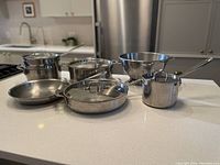 Overview of entire set on countertop showing all pots, pans and colander.
