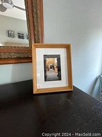 Framed photo titled "Peru" by Avner Ofer displayed on black surface, showing wooden frame and white matting
