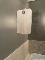 Front view of the rectangular mirror suction-attached to a shower wall above tile, showing size and attachment.