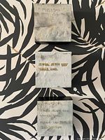 Three small square mixed media art boxes featuring lost dog notices about a black dog named Karl, arranged on black and white patterned fabric.