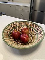 Top view of the basket holding three red apples; shows depth and overall shape on a kitchen countertop.