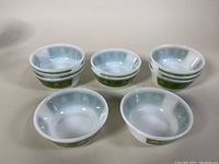 Ten vintage milk glass cereal bowls grouped and stacked in sets of two or three, showing the exterior and interior light blue swirl pattern.