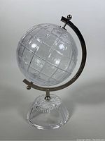 Front view of the textured crystal globe on its base with metal semi-circle arm