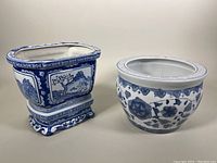 Two Chinese blue and white porcelain planter pots displayed together. Left pot is rectangular with two-piece design including a stand. Right pot is round with floral pattern.