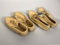 Two pairs of tan leather moccasins with original tags, side by side.