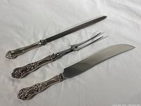 Full set showing knife sharpener, carving fork, and carving knife with sterling silver handles and stainless steel blades and rod.