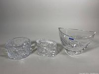 Three Waterford cut crystal pieces displayed side by side: a vase, a trinket box, and one of two bowls.