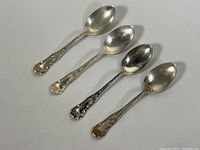 Four sterling silver teaspoons displayed side by side on white background showing overall pattern and shape