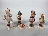 Front view of four vintage Goebel Hummel porcelain figurines showing detailed hand-painted features.