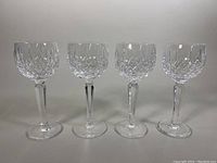 Front view of all four Waterford hock wine glasses in a row showing their shape and cut pattern details.