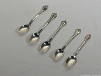 Image showing five sterling silver coffee spoons arranged in a line, all measuring approximately 4.25 inches. Four spoons have the same ornate handle style (Birks), and one has a slightly different design.