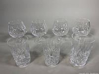 Full view of seven Waterford cut crystal glasses showing four stemmed glasses in back row and three tumblers in front row.
