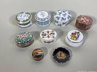Eight assorted vintage trinket boxes of varied shapes and materials arranged on a neutral background.