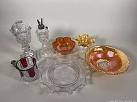 Wide view of the lot showing all items including oil lamps, carnival glass bowls, and clear glass dishes.