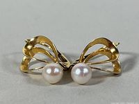 Close-up front view showing the symmetrical design of the gold earrings with round white pearls.