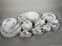 Full set spread showing all components including plates, bowls, cups, gravy boat, sugar bowl, and creamer with floral design on white bone china.