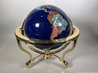 Full view of the globe and brass frame stand, showcasing lapis lazuli ocean and inlaid gemstones.