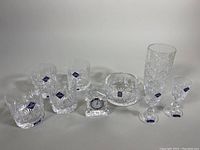 Photo showing the full lot of crystal glassware items including goblets, tumblers, bowls and small mantle clock all with Edinburgh Crystal labels.