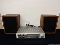 Full view showing the stereo receiver centered between the two wooden speakers with black fabric grills