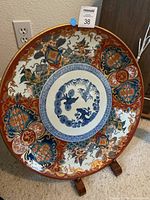 19-inch Japanese porcelain platter with detailed multi-color floral and ornamental designs on wooden stand