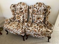 Front view of two floral wingback chairs placed side by side showing the fabric pattern and cushions.