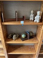 Top shelf showing pair of ceramic child figure book ends in light beige or off-white color, children reading books.
