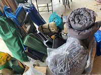 Photo of camping chairs, sleeping bags, and tarps piled together.