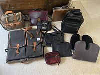 Full view of various bags and cases arranged on the floor showing the assortment of carry cases including garment bag, briefcases, and pouches.