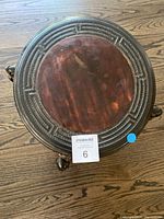 Top view of the round plant table showing the polished reddish-brown marble top inset into the carved wooden frame with geometric patterns.