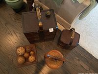 Full view of three baskets of different sizes with decorative wicker balls on square tray, showing various woven patterns and metal hardware.