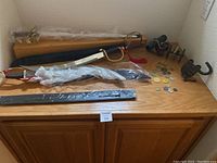 Overall view of both decorative swords with scabbards, cannon models, padlock and coins arranged on wooden surface