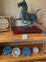 Top shelf showing two brass clocks and two horse sculptures