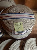 Close-up of top fabric strapping tape roll showing red and blue stripes pattern and material texture.