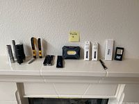 Overall view of all items on a white mantel: multiple flashlights, work lights, laser pointers, and packaging boxes.